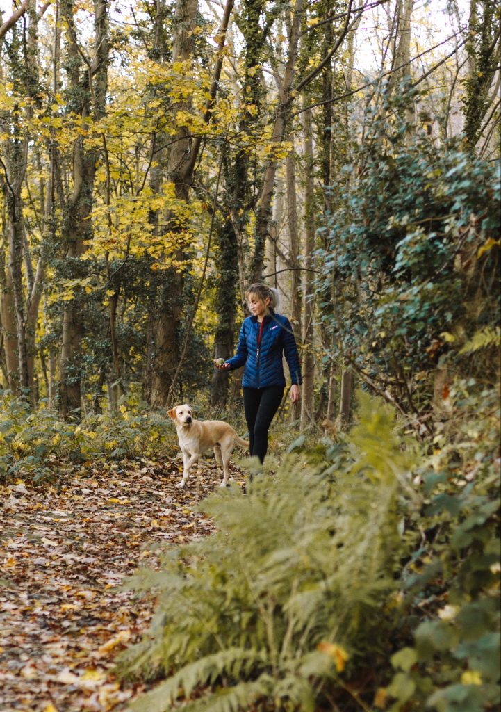 Woman walking yellow lab dog in woods