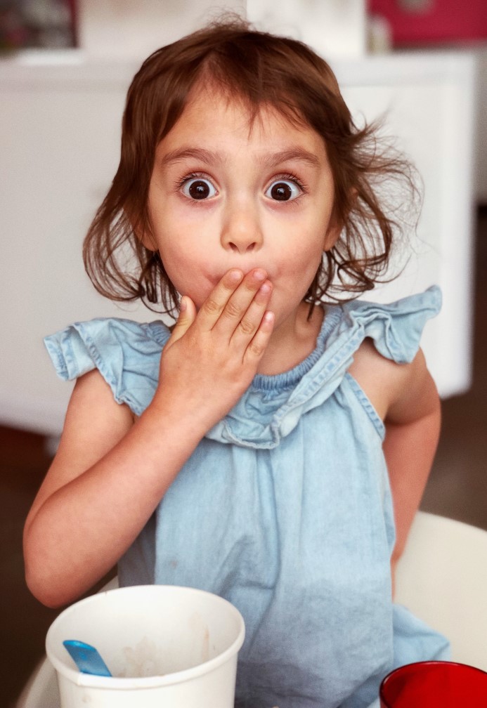 Dismayed girl with her hand over her mouth and wide eyes because dog is leaking urine