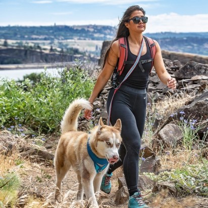 woman hiking with dog using kurgo quantum leash in over shoulder position